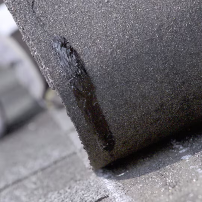 Close-up of Dura Grip adhesive bond on shingles engineered by GAF to improve wind resistance and seal strength in asphalt roofing systems