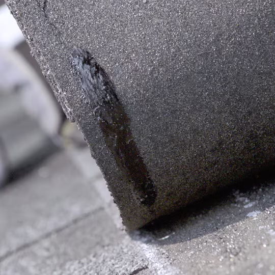 Close-up of Dura Grip adhesive bond on shingles engineered by GAF to improve wind resistance and seal strength in asphalt roofing systems