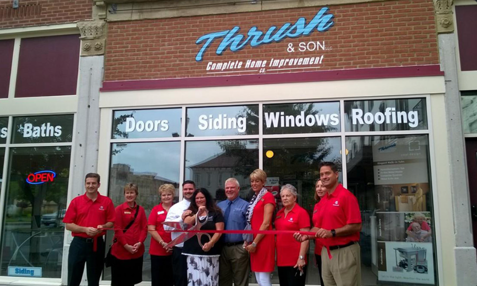 Family-owned Thrush & Son team celebrating ribbon cutting outside their Troy showroom offering roofing, siding, windows, doors, and baths