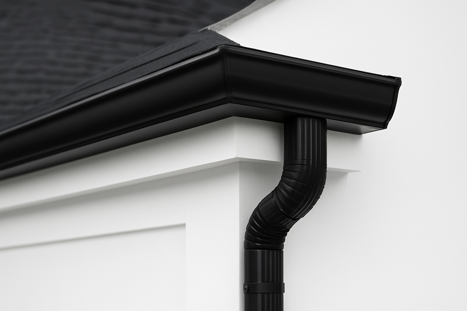 Siding, Soffit & Gutter Terminology: Modern white home exterior corner with black seamless gutters and downspout, showcasing gutter installation services.