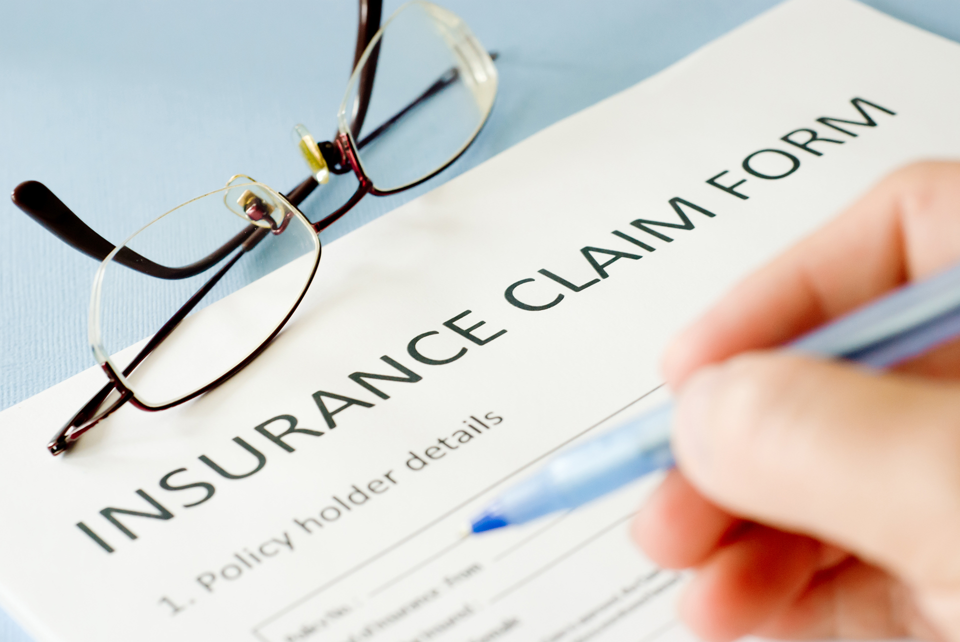 Homeowner filling out insurance claim form after storm damage