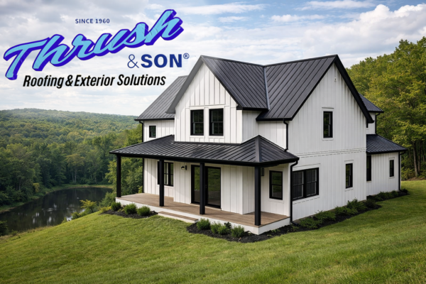 Modern farmhouse with white steel siding in a board-and-batten design, black metal roof, black window trim, and black gutters overlooking wooded landscape and pond.