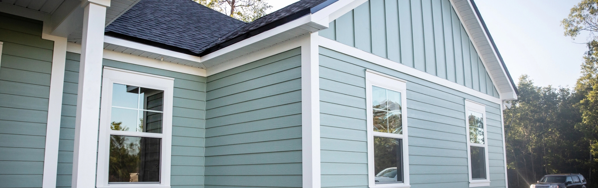 Sage green lap siding and board-and-batten vertical siding with white trim, columns, and soffit on a Dayton, Ohio home